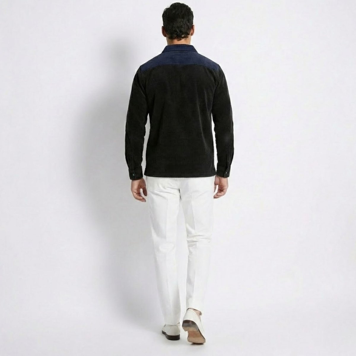 Back view of the Kouvr Zain Black Corduroy Polo, highlighting the navy contrast collar detail and textured fabric.