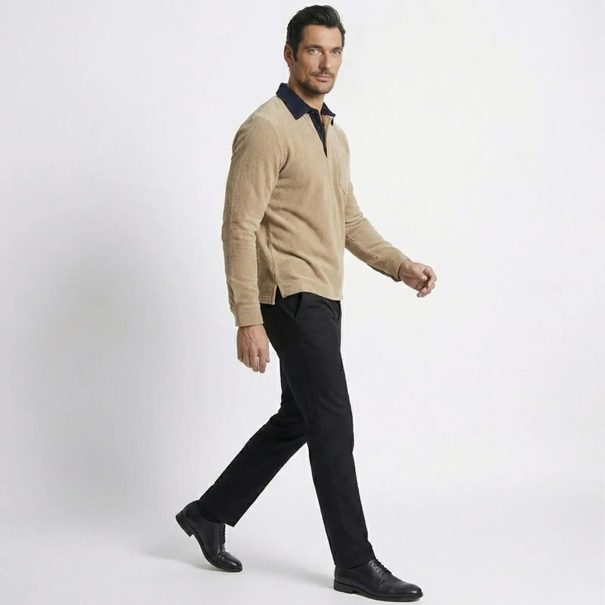 Side profile of a man walking in the Kouvr khaki corduroy polo and black trousers, showcasing the shirt's fit and movement.

