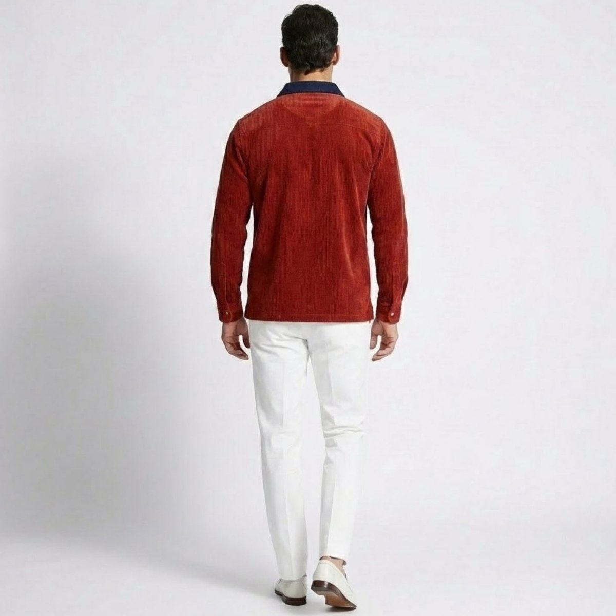 Back view of a model wearing the Kouvr Zian red corduroy polo shirt, highlighting the navy collar and shirt structure. 