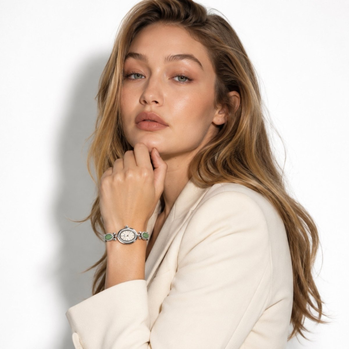 Fashion model wearing a beige blazer accessorized with the Kouvr gold vintage women's watch with green stones.