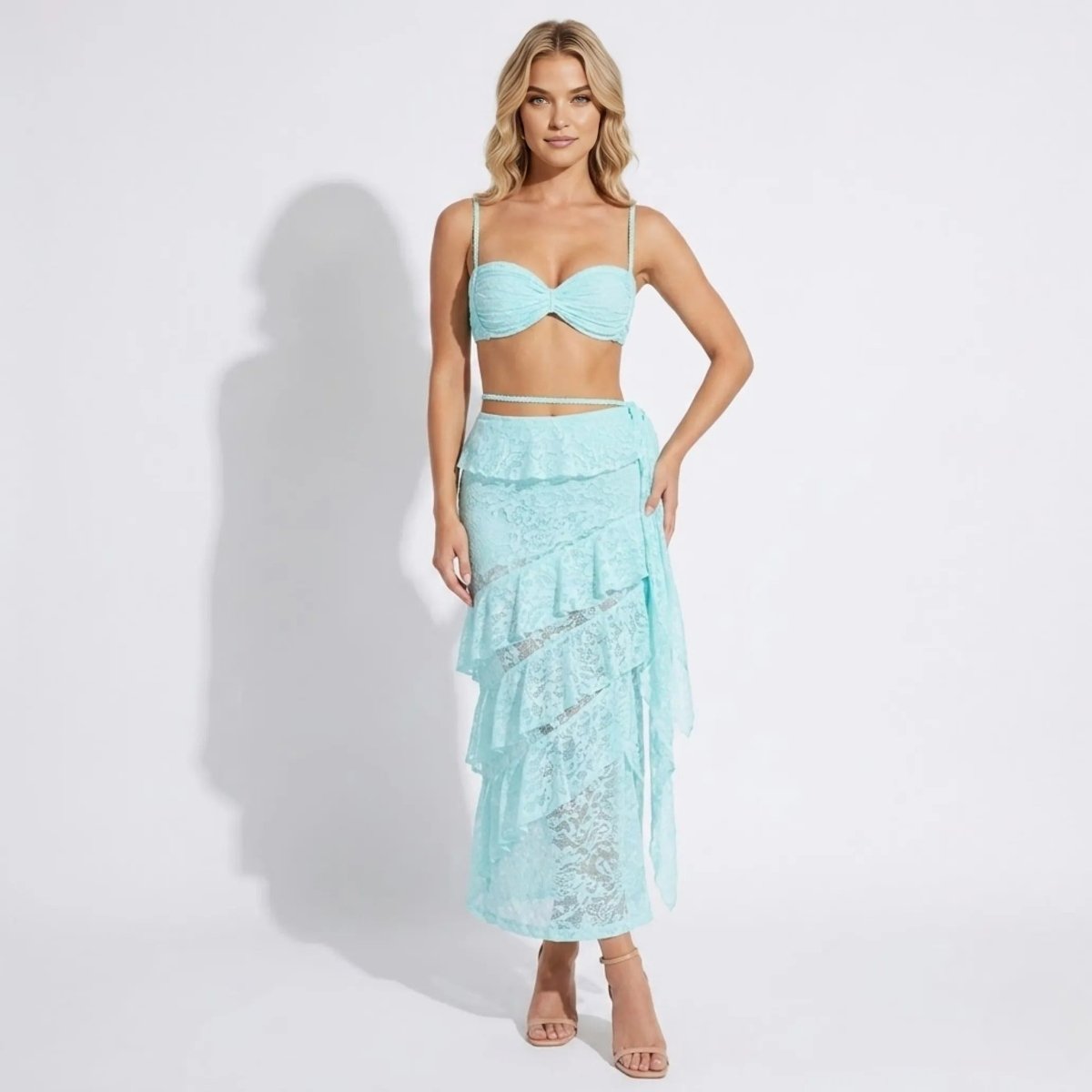 Woman wearing a luxury light blue lace tiered ruffle maxi skirt and matching ruched bralette two-piece set by Kouvr.