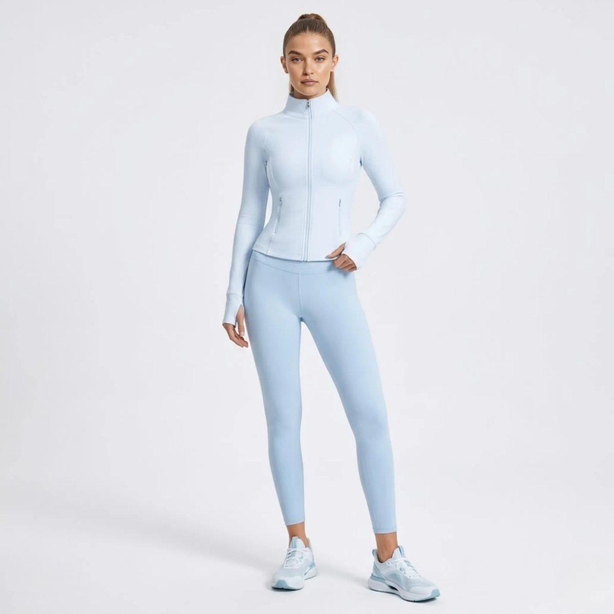 Side profile of woman walking in Kouvr light blue athletic jacket featuring functional thumbholes.