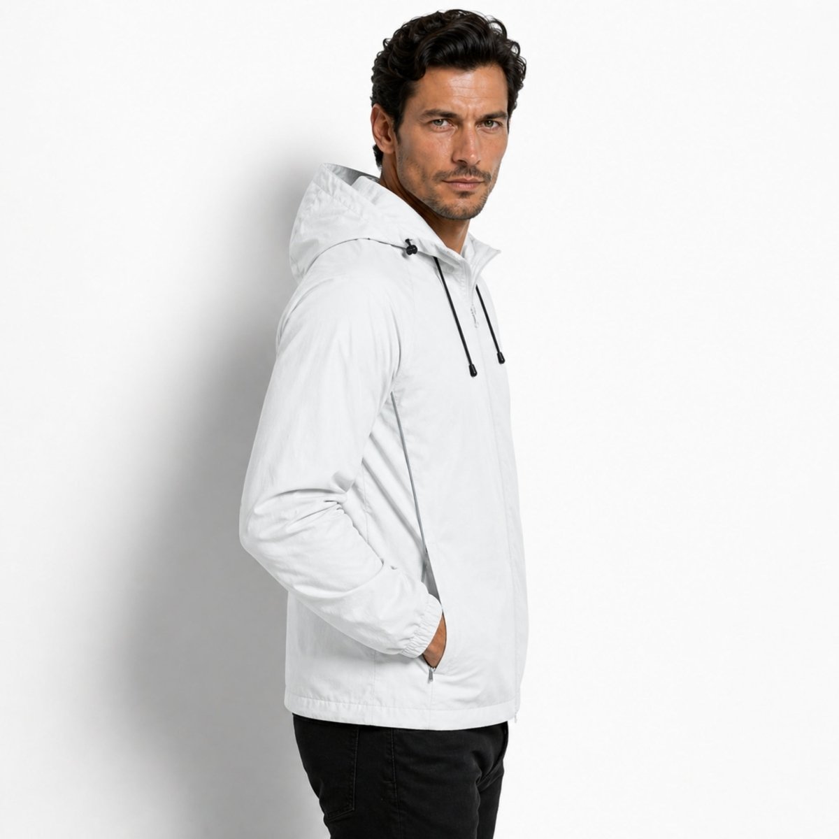 Side profile of a male model in a light grey water-resistant jacket highlighting the raglan sleeves and tailored hood design.
