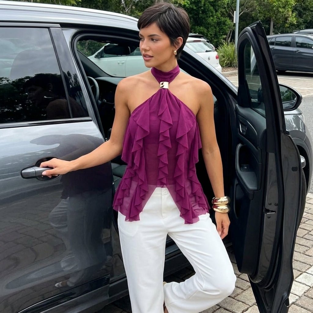 Woman with short dark hair stepping out of a car wearing an elegant plum ruffle halter evening blouse.