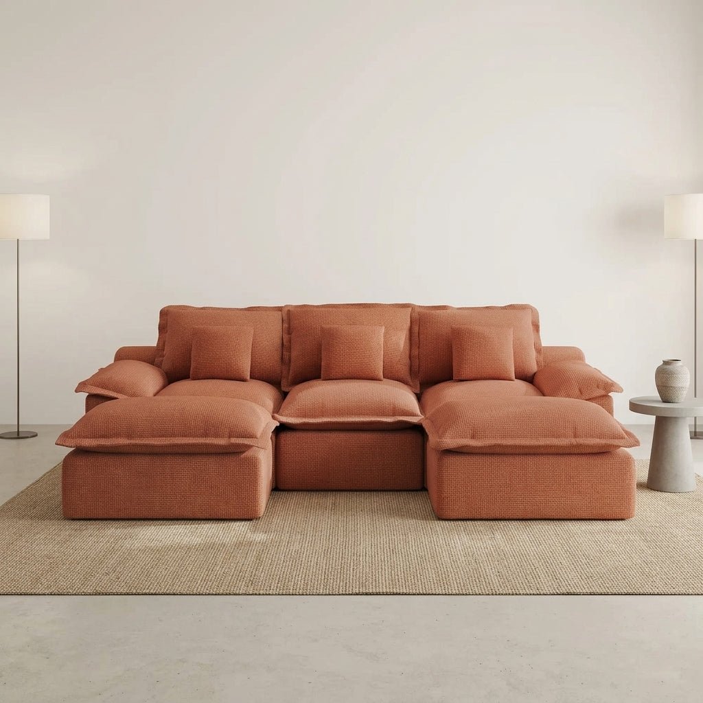 High-end modular sofa in a terracotta shade placed in a luxury penthouse living room with marble floors and city views.