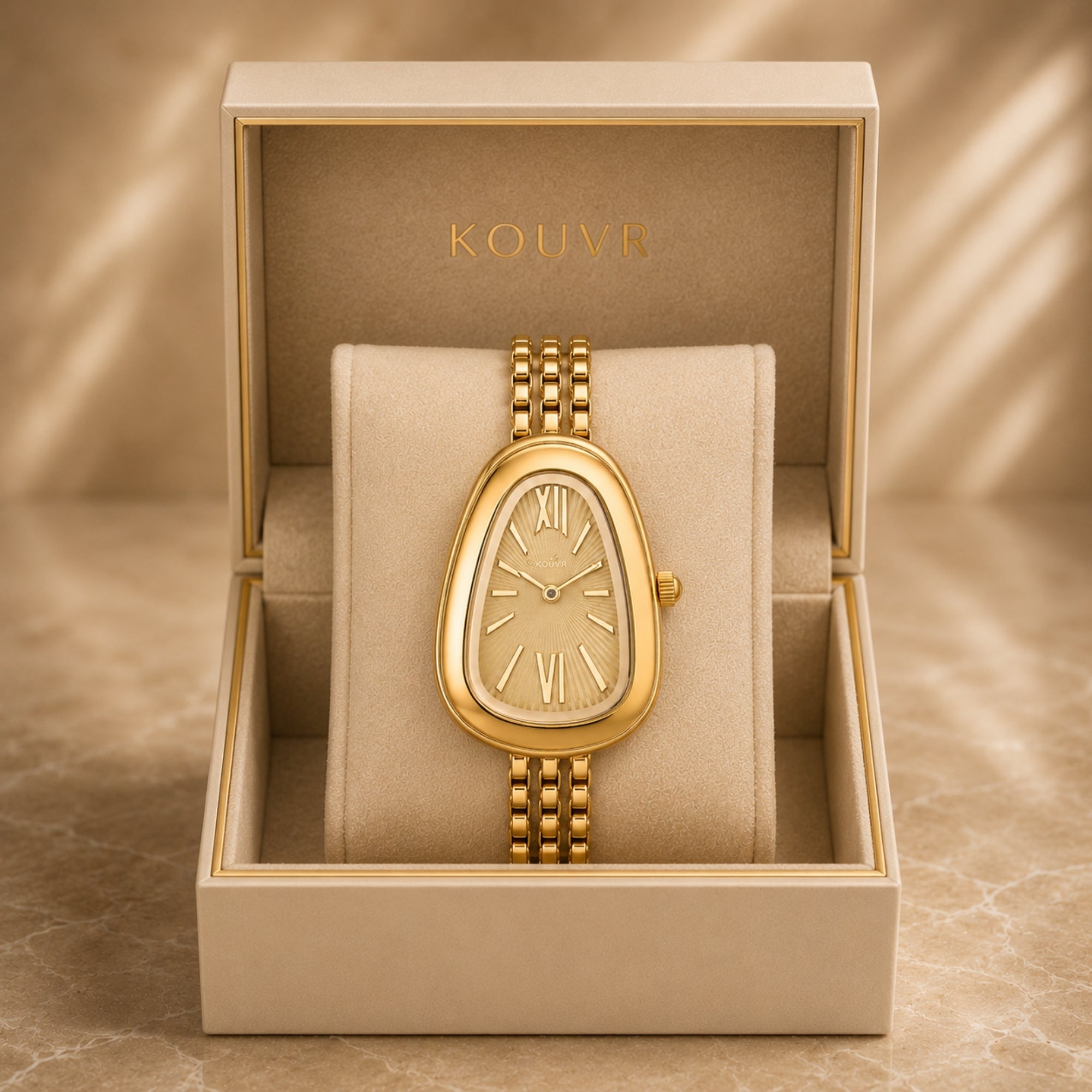 Kouvr luxury women's vintage style gold watch with asymmetrical teardrop dial presented in a premium beige gift box.