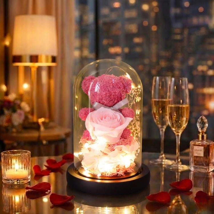Magenta pink moss bear with a preserved rose in a glowing glass dome next to a luxury perfume bottle.