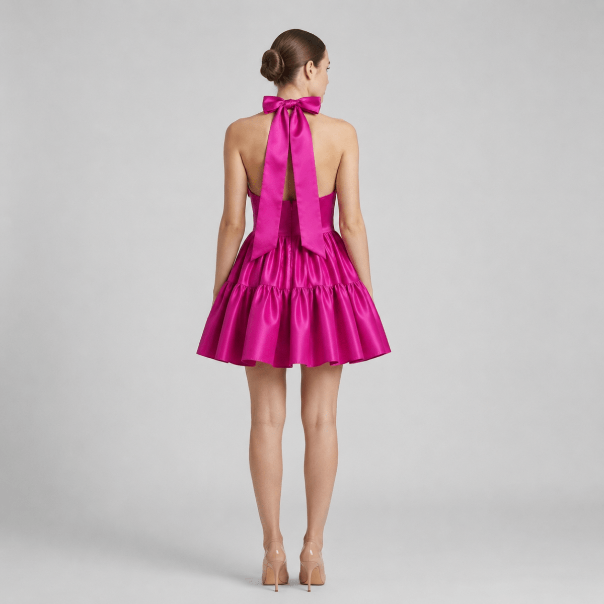 Back view of the Kouvr magenta pink satin mini dress showing the dramatic oversized bow tie back and voluminous ruffled skirt.