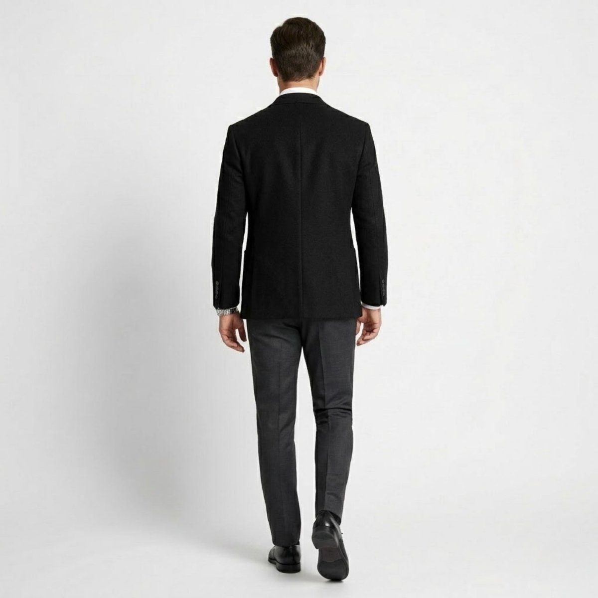 Full body back view of black wool blend blazer and dark grey dress pants in motion.