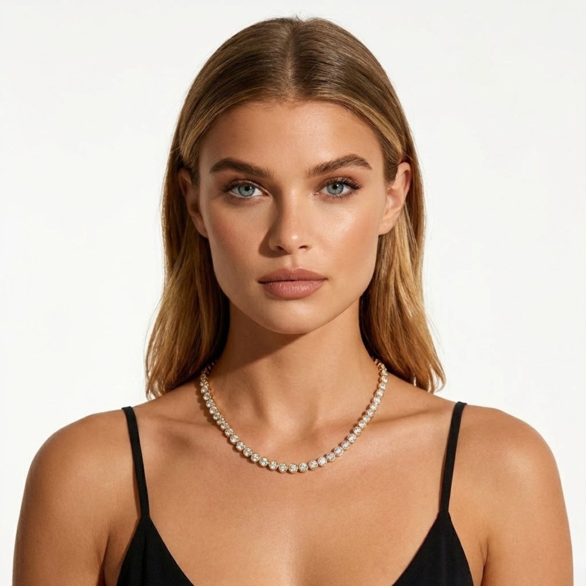 A woman with blonde hair looking directly at the camera, wearing the Kouvr Aaliyah diamond tennis necklace with a black top.