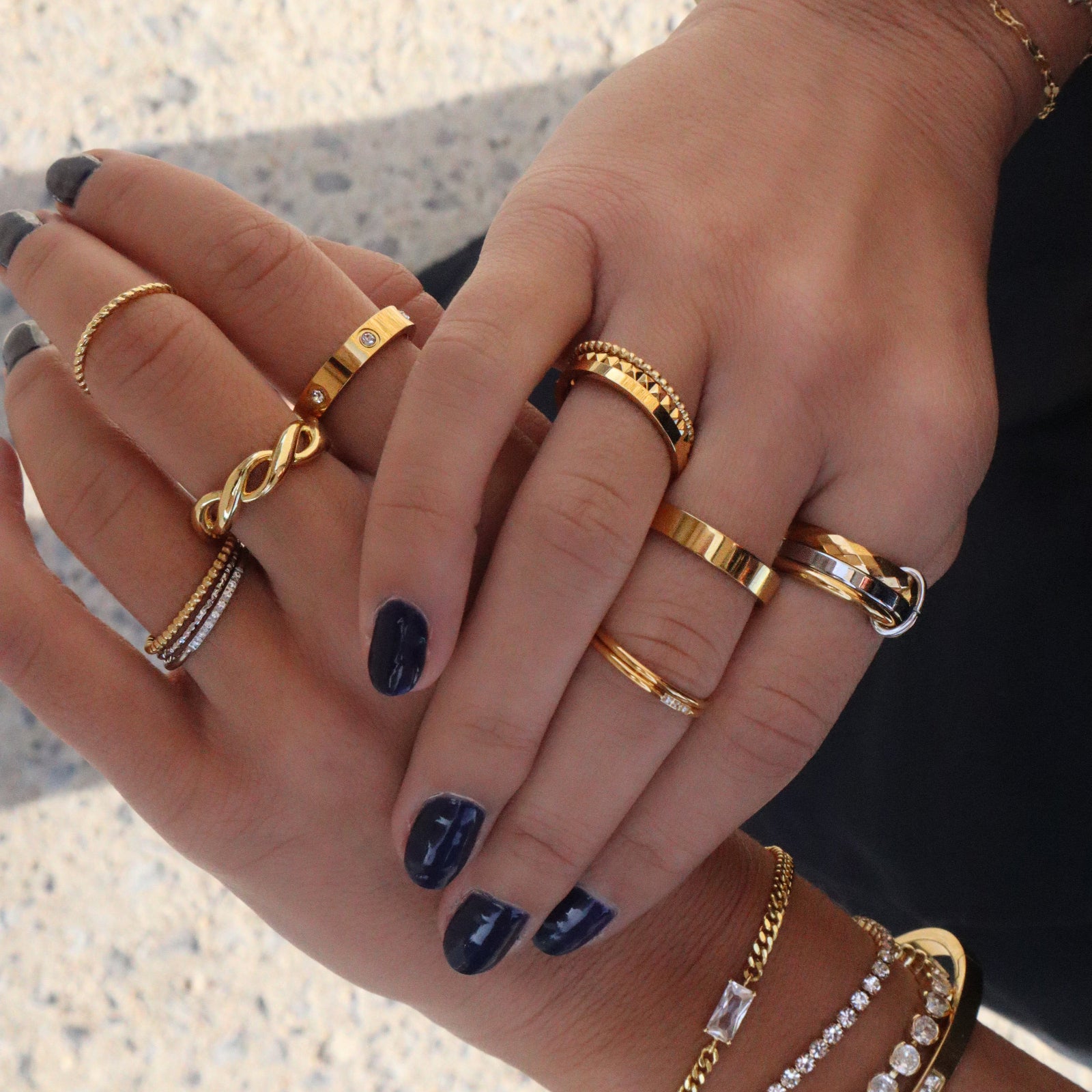 A model's hand wearing a stack of gold rings from Kouvr Fashion, featuring the Zephira Diamond Ring.