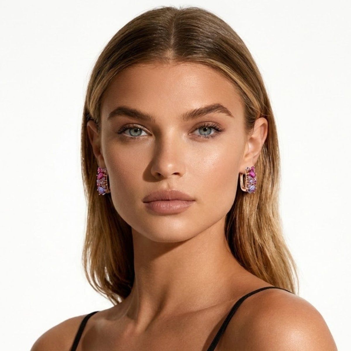 A blonde model with blue eyes wearing Kouvr Millie multi-gemstone cluster huggie earrings, showcasing their size and vibrant color.