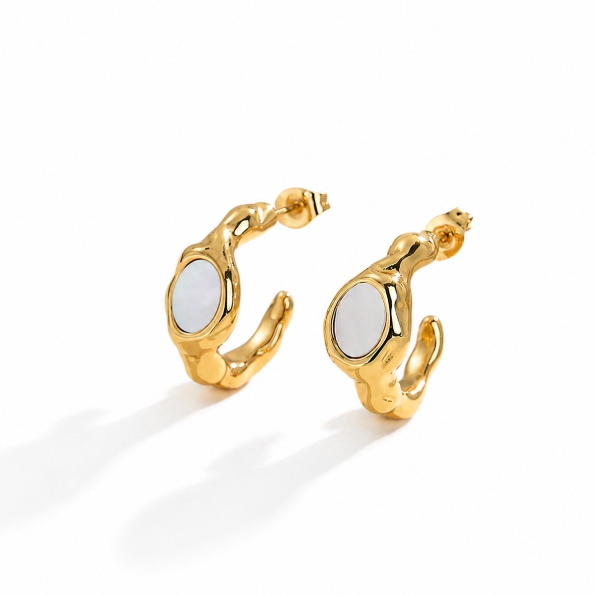 Pair of molten chunky gold hoop earrings with irregular organic shape and white mother of pearl inlay on a crisp white background.
