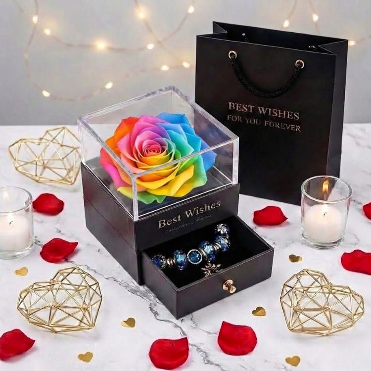 A colorful rainbow forever rose in a clear-top jewelry box, displayed on a marble surface with romantic decor.