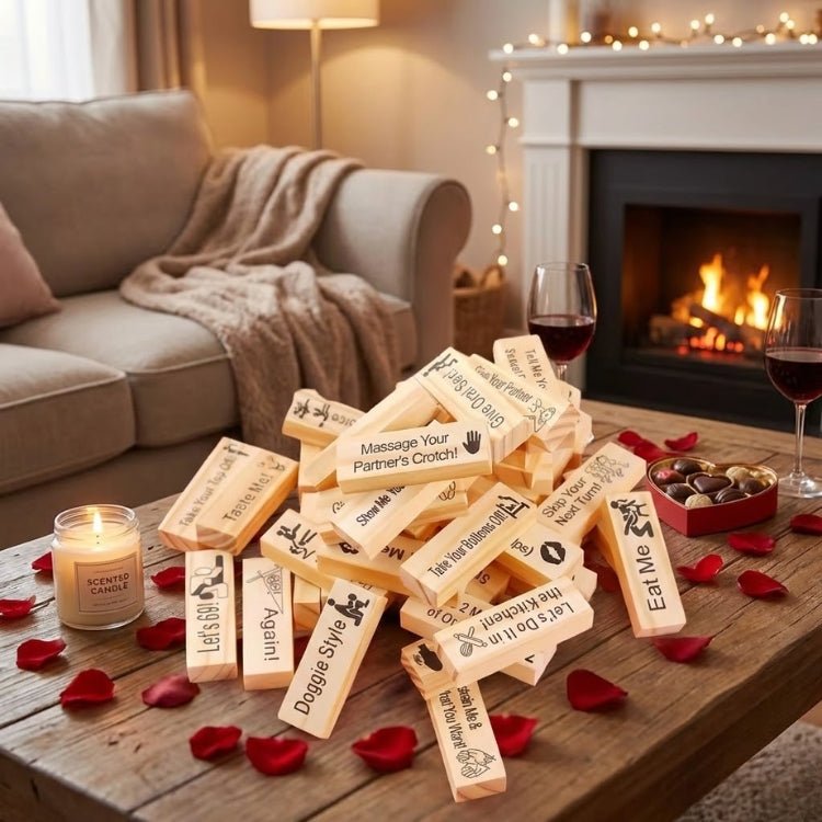 A pile of 48 naughty wooden blocks for adults with explicit prompts like "Doggie Style" and "Let’s 69" next to a scented candle and glasses of red wine.