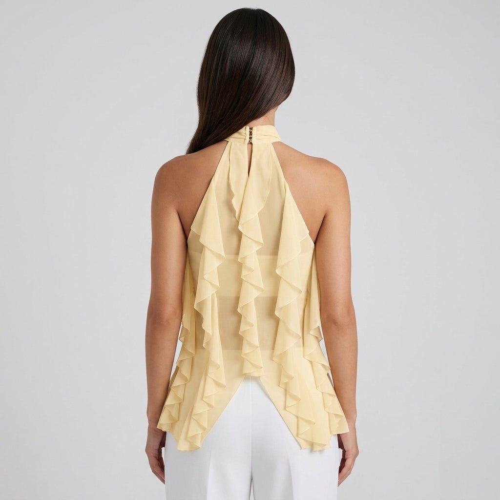  Back view of woman wearing pale yellow sheer ruffle halter blouse showing split hem design and sheer fabric details.