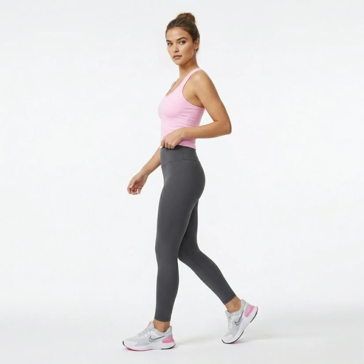 Side profile of model walking in the Kouvr pink form-fitting activewear crop top demonstrating garment stretch and fit