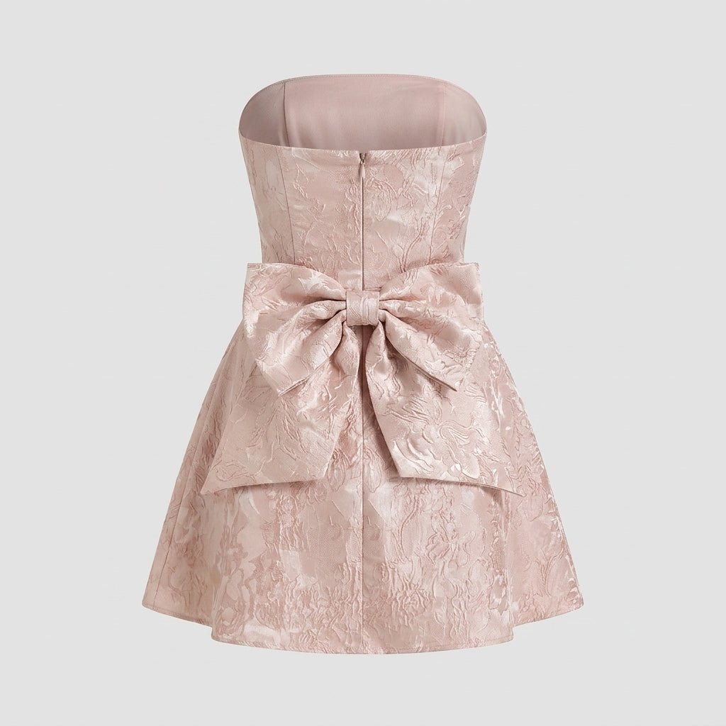 Studio flat lay product back view of a pink formal mini dress showcasing the large structural bow detail.