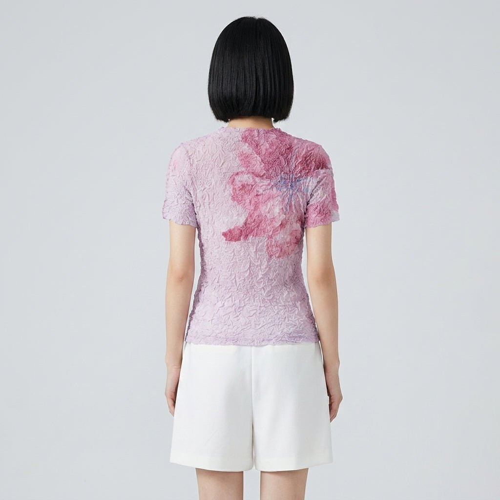 Back view of woman wearing Kouvr pink and magenta floral crinkle short sleeve top with white shorts