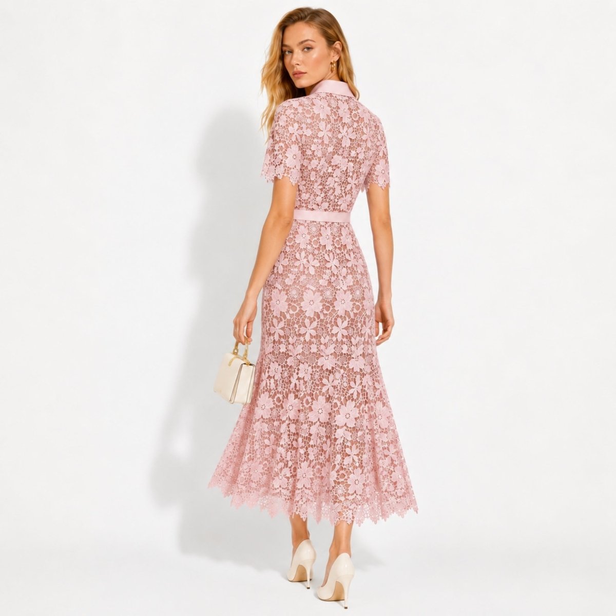 Back view of women's pink short sleeve lace wedding guest midi dress highlighting fitted waist and scalloped hem