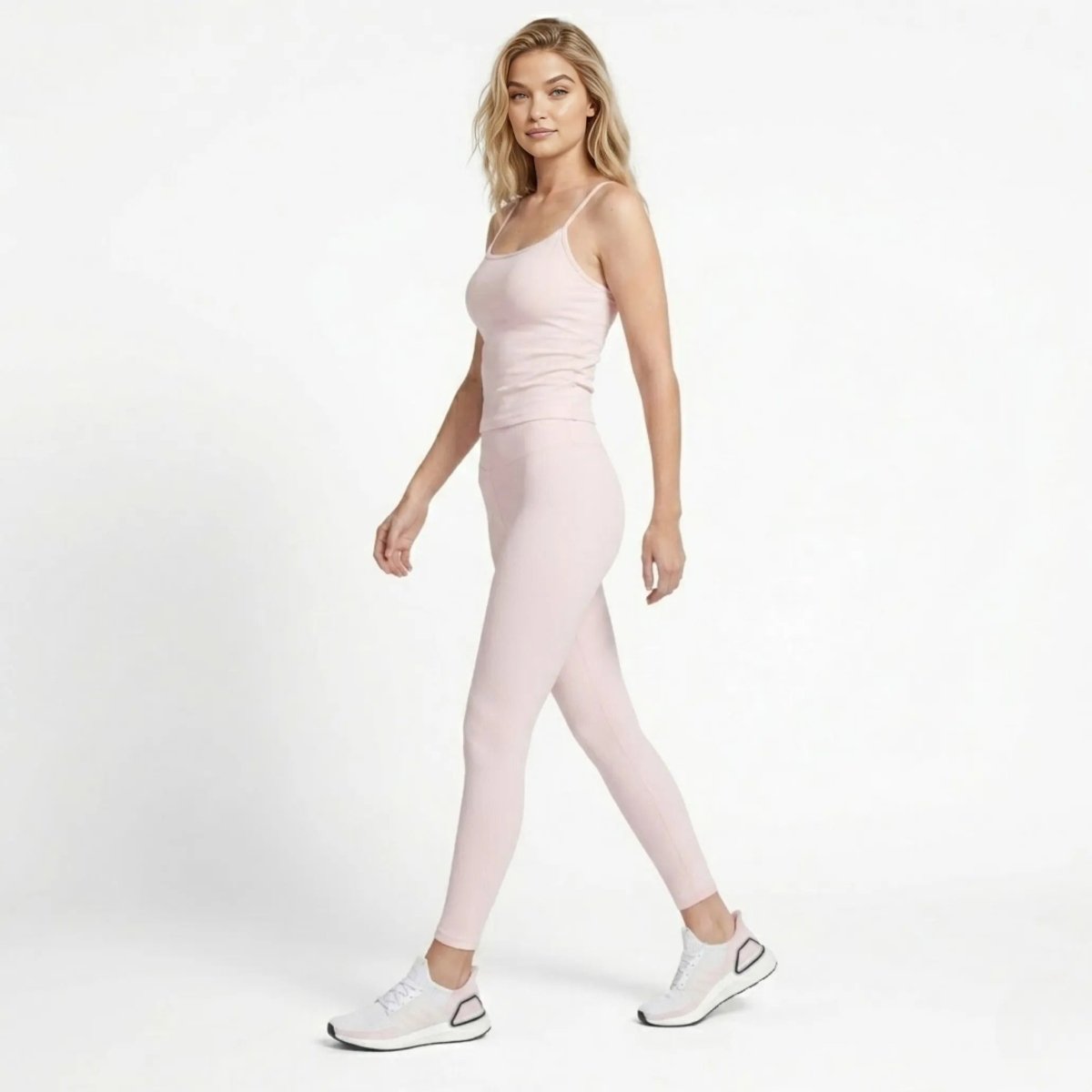 Woman walking confidently in high end blush pink ribbed legging and tank outfit.