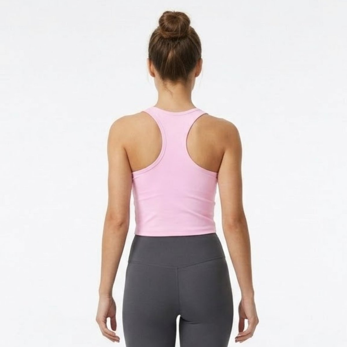 Back view of female model showcasing the athletic racerback design of the Kouvr light pink sculpting crop top 