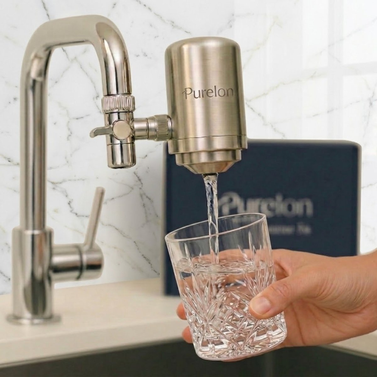 A Pureion stainless steel faucet-mounted water filter pouring fresh, clean water into a crystal glass in a modern kitchen.