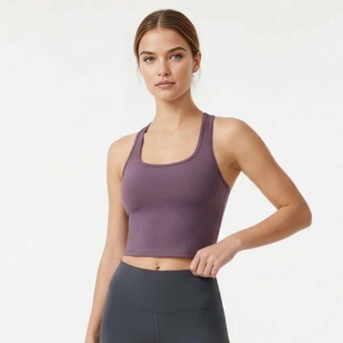 Woman wearing Kouvr purple scoop neck racerback activewear crop top front view.