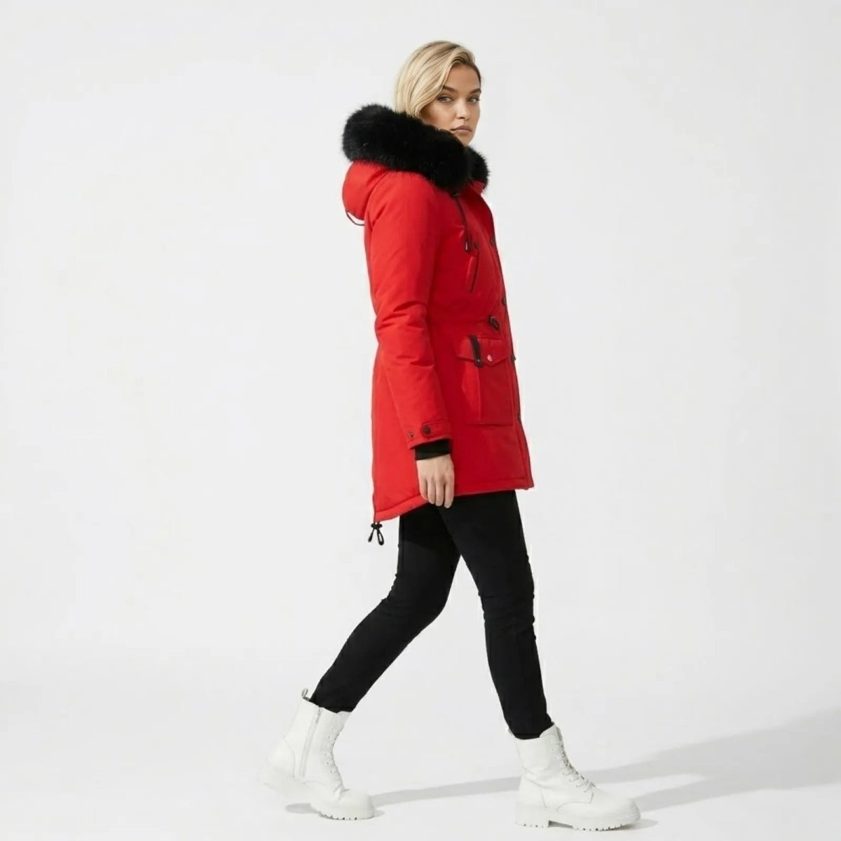 Side view of woman walking in Kouvr red mid-length winter coat with drawstring waist