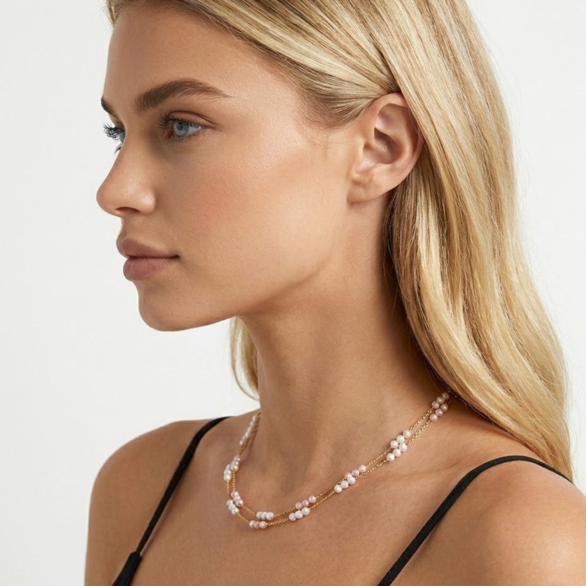  Side view of a model showcasing how the Kouvr Josie double strand pink and white pearl necklace sits on the collarbone.