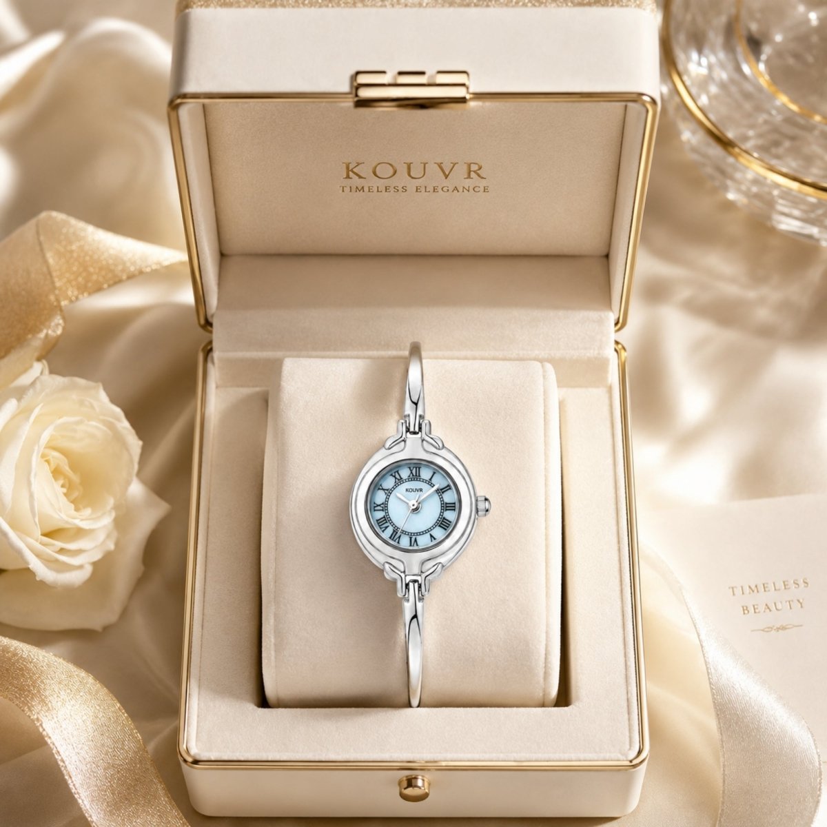 Kouvr women's silver bangle watch with light blue dial displayed in a luxury cream presentation box.