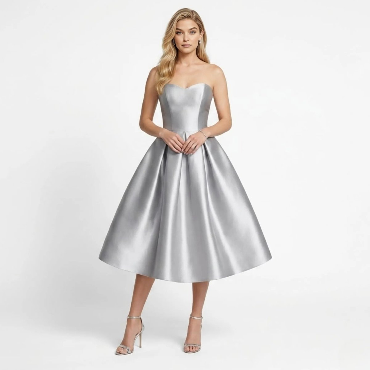 Front view of model wearing a silver strapless satin midi dress with sweetheart neckline and pleated skirt.
