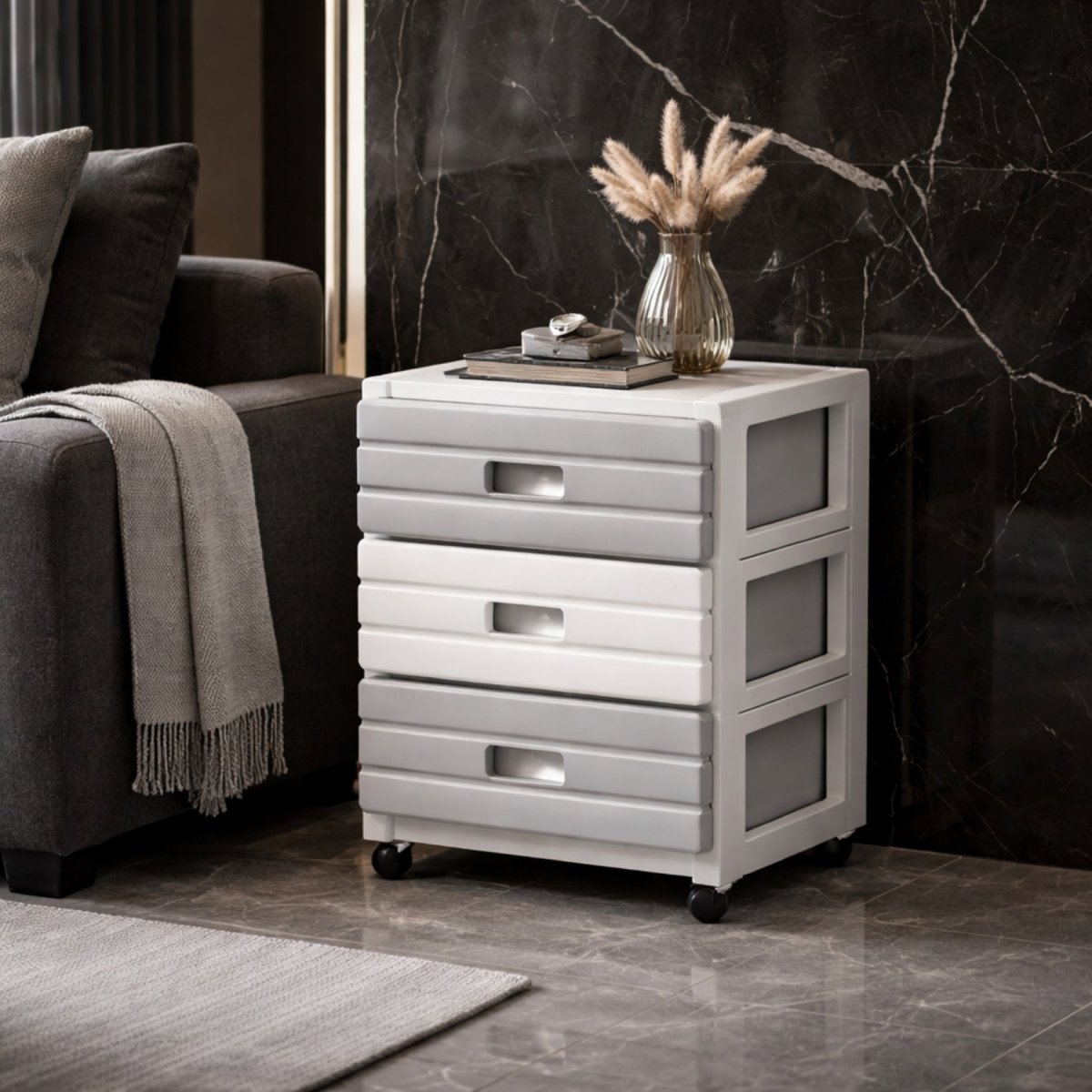 Small three-tier grey and white rolling storage cabinet functioning as an elegant side table next to a dark sofa.