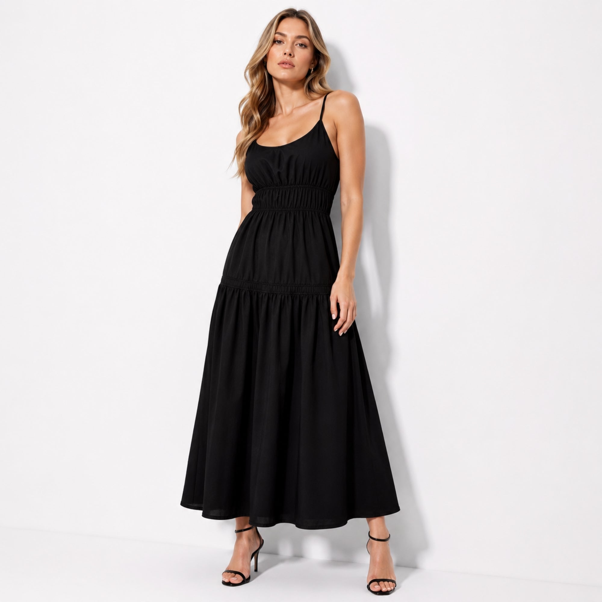 Woman wearing a sophisticated black smocked waist tiered maxi dress