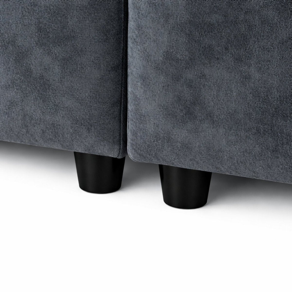 Hand pressing deep into ultra-plush dark grey sofa cushion demonstrating premium sink-in comfort