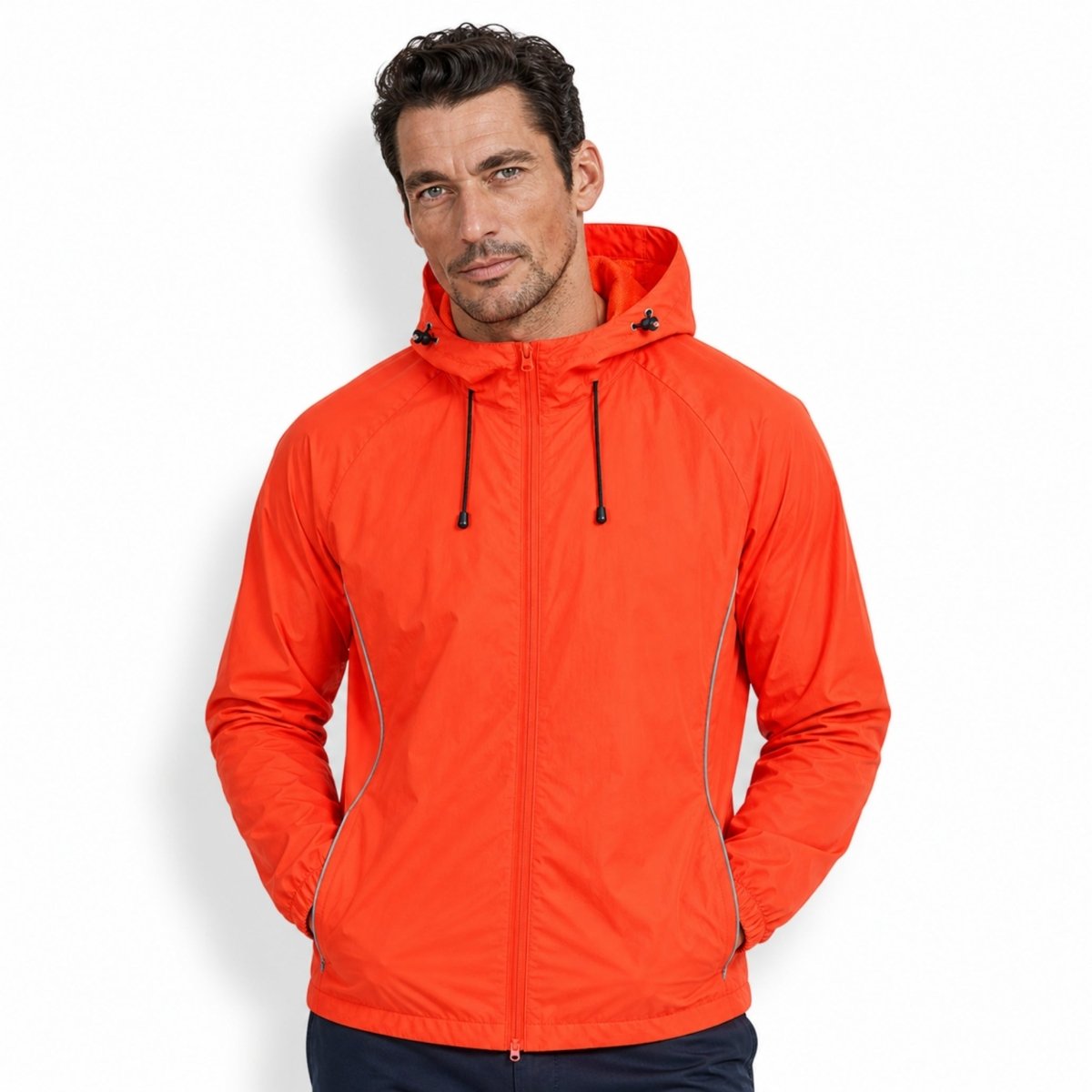 Handsome male model wearing Kouvr bright orange water-resistant zip-up activewear jacket showing unisex fit and styling.