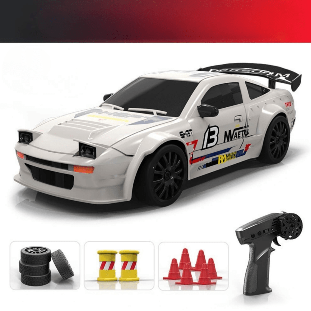 White and black drift RC car, resembling a Toyota AE86, displayed with a remote control, spare tires, traffic cones, and oil drums.