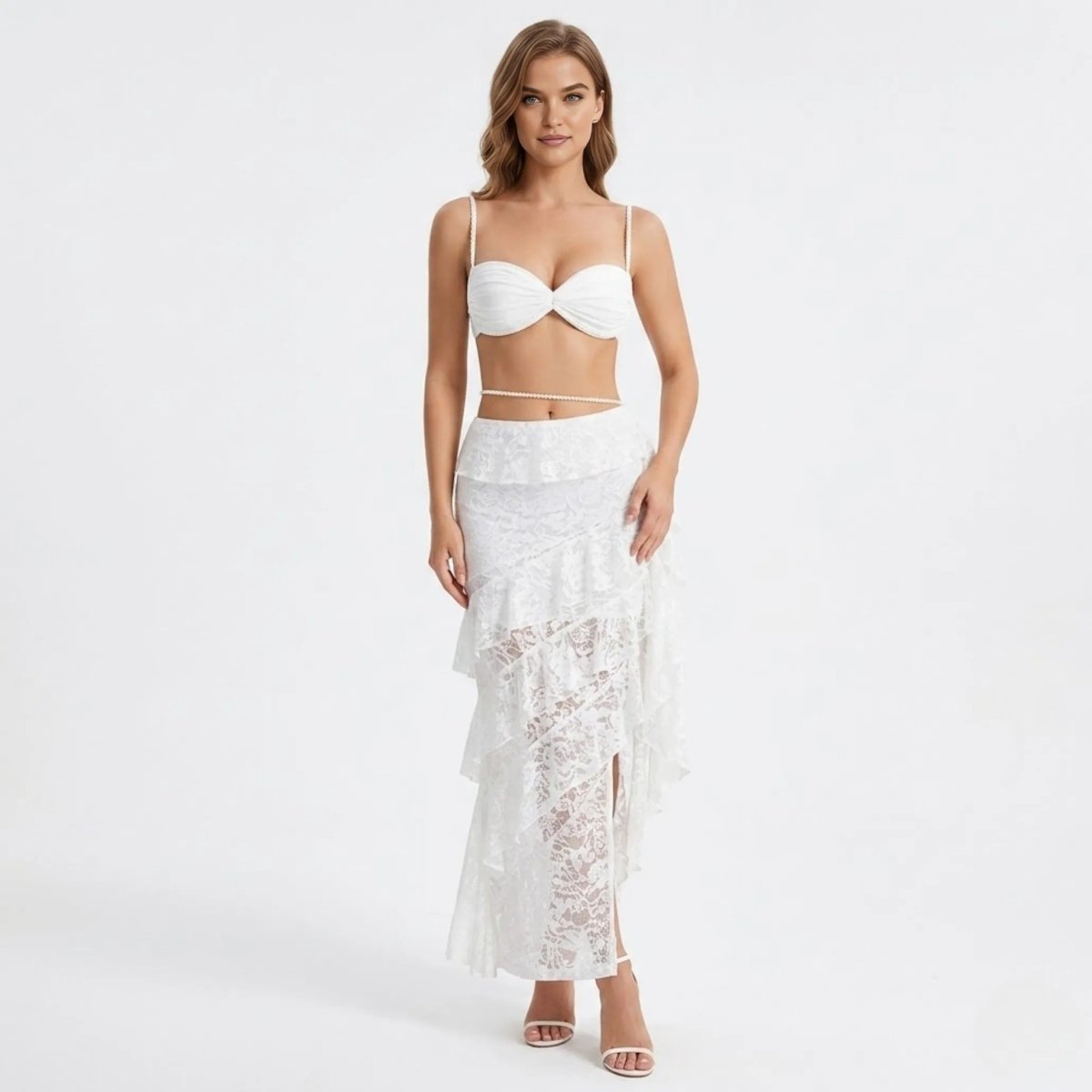 Front view of the Kouvr white lace tiered ruffle maxi skirt and pearl strap bralette two piece set worn by a blonde model.