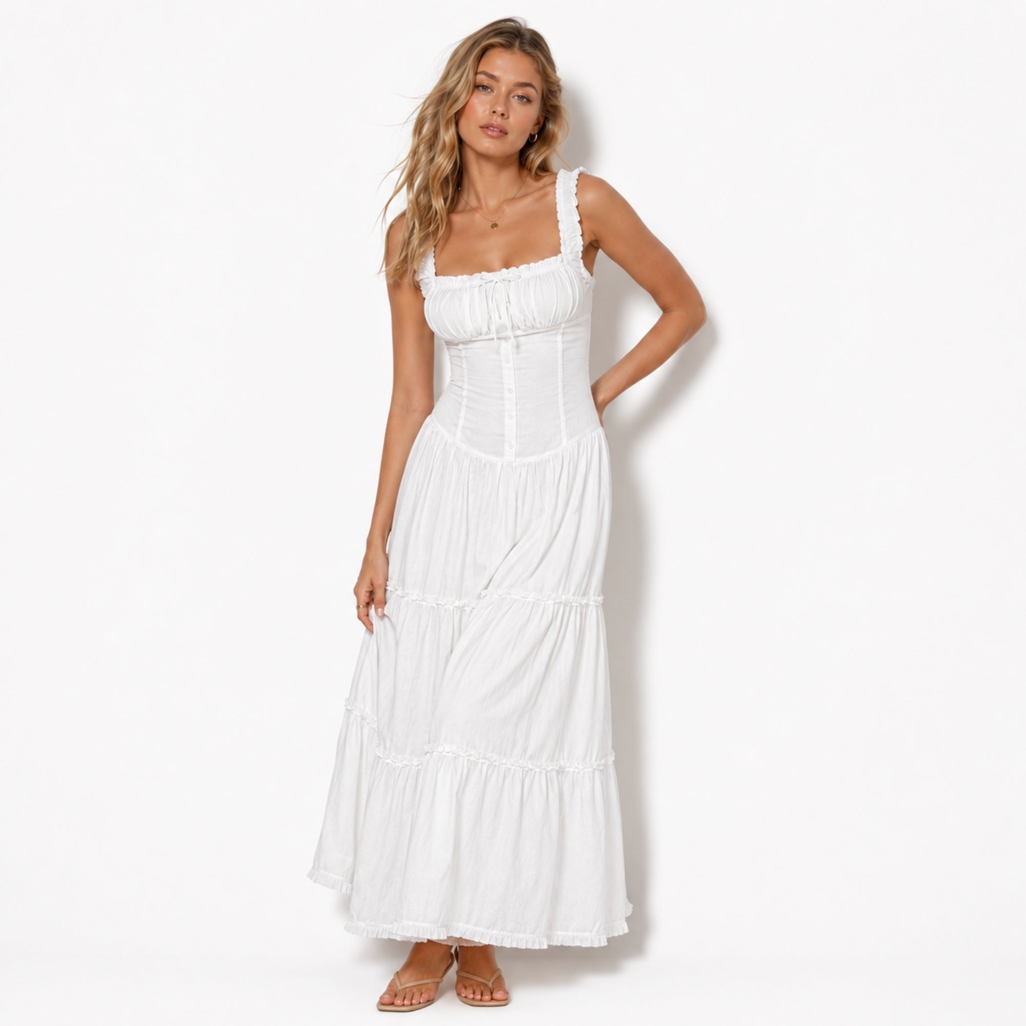 Full length front view of a model wearing a white luxury vacation maxi dress with tiered ruffle skirt and elegant square neckline.