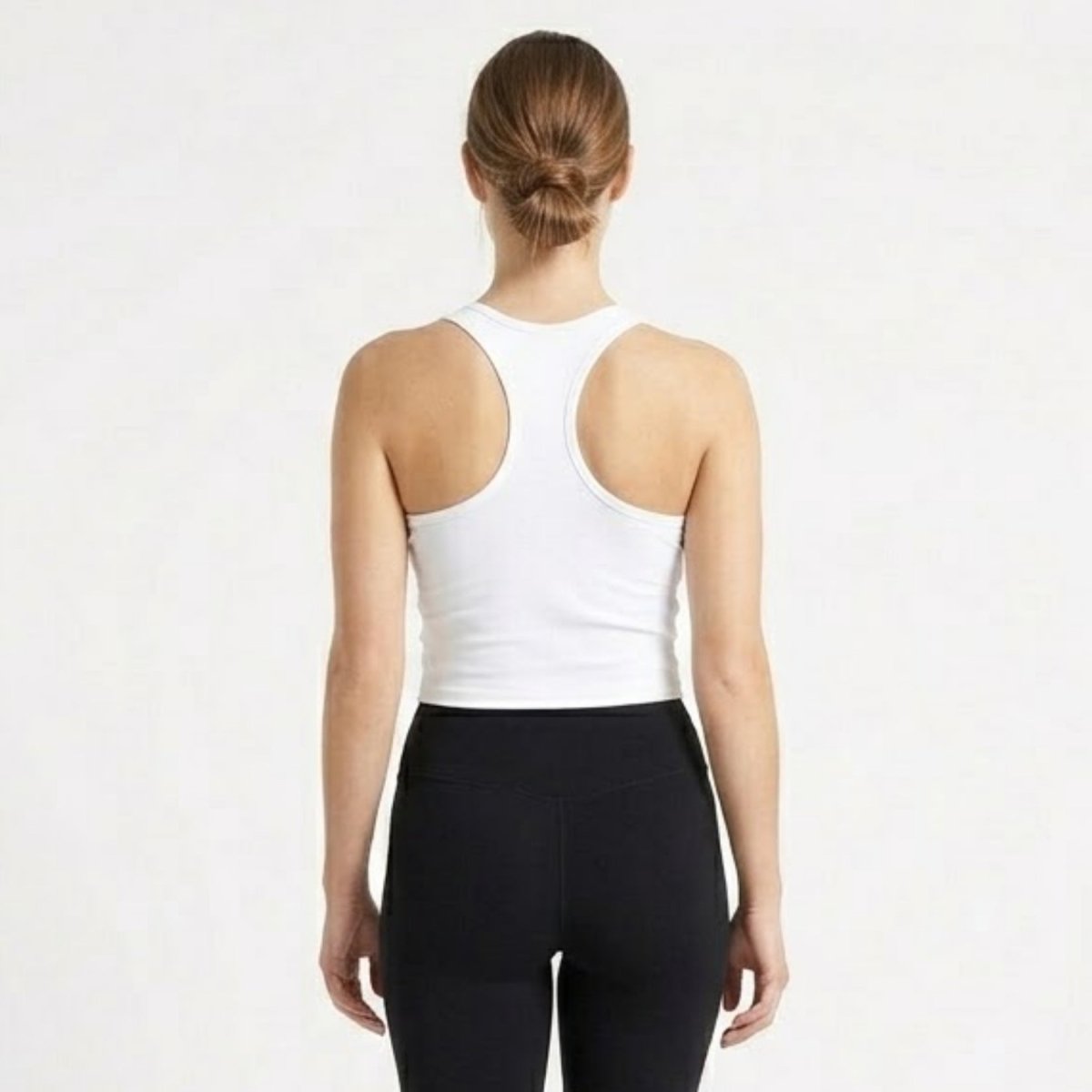 Back view of woman wearing a fitted white athletic racerback crop top.