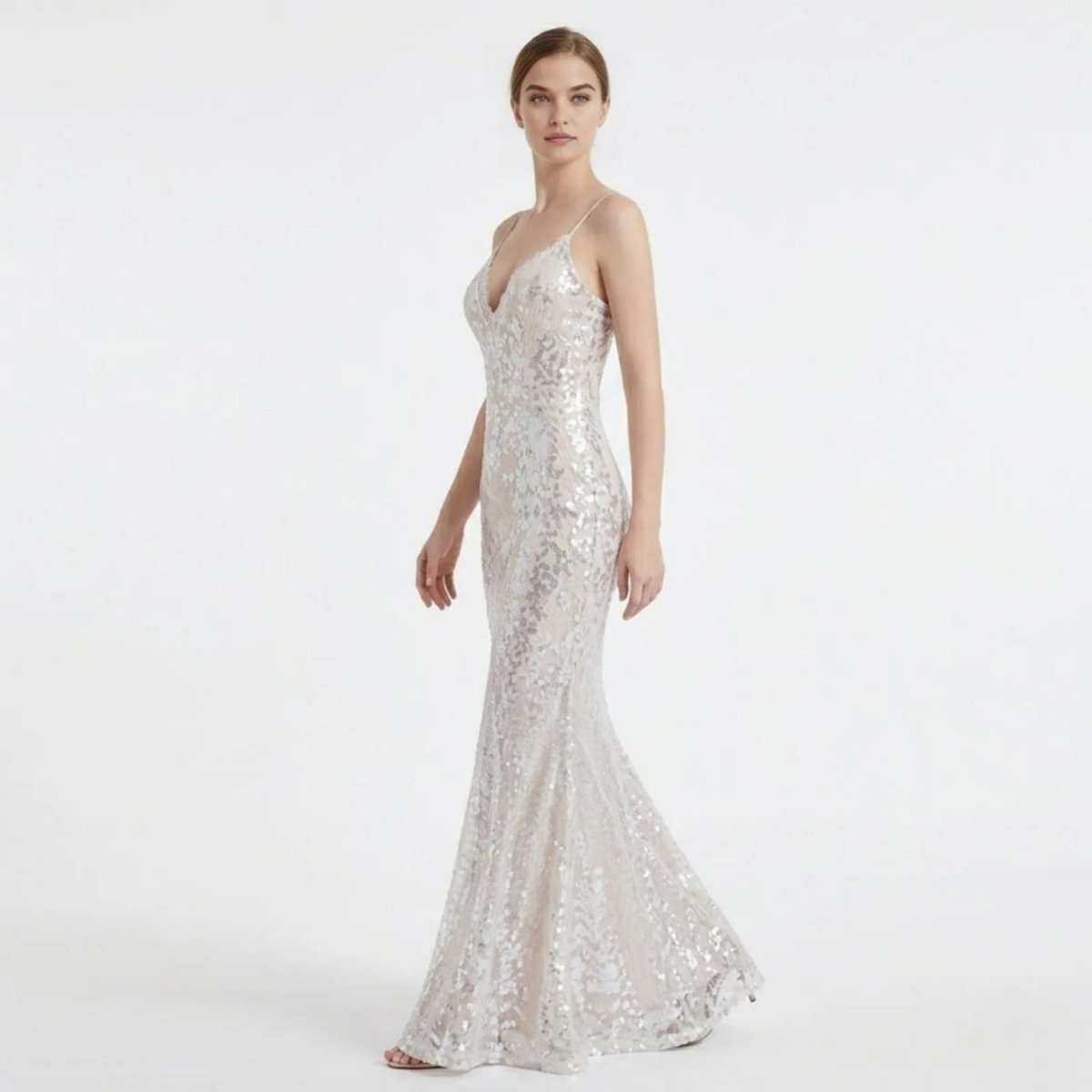 Side angle profile of a woman in a sparkling white sequin maxi prom dress, showcasing the form-fitting bodycon silhouette and thin spaghetti straps.