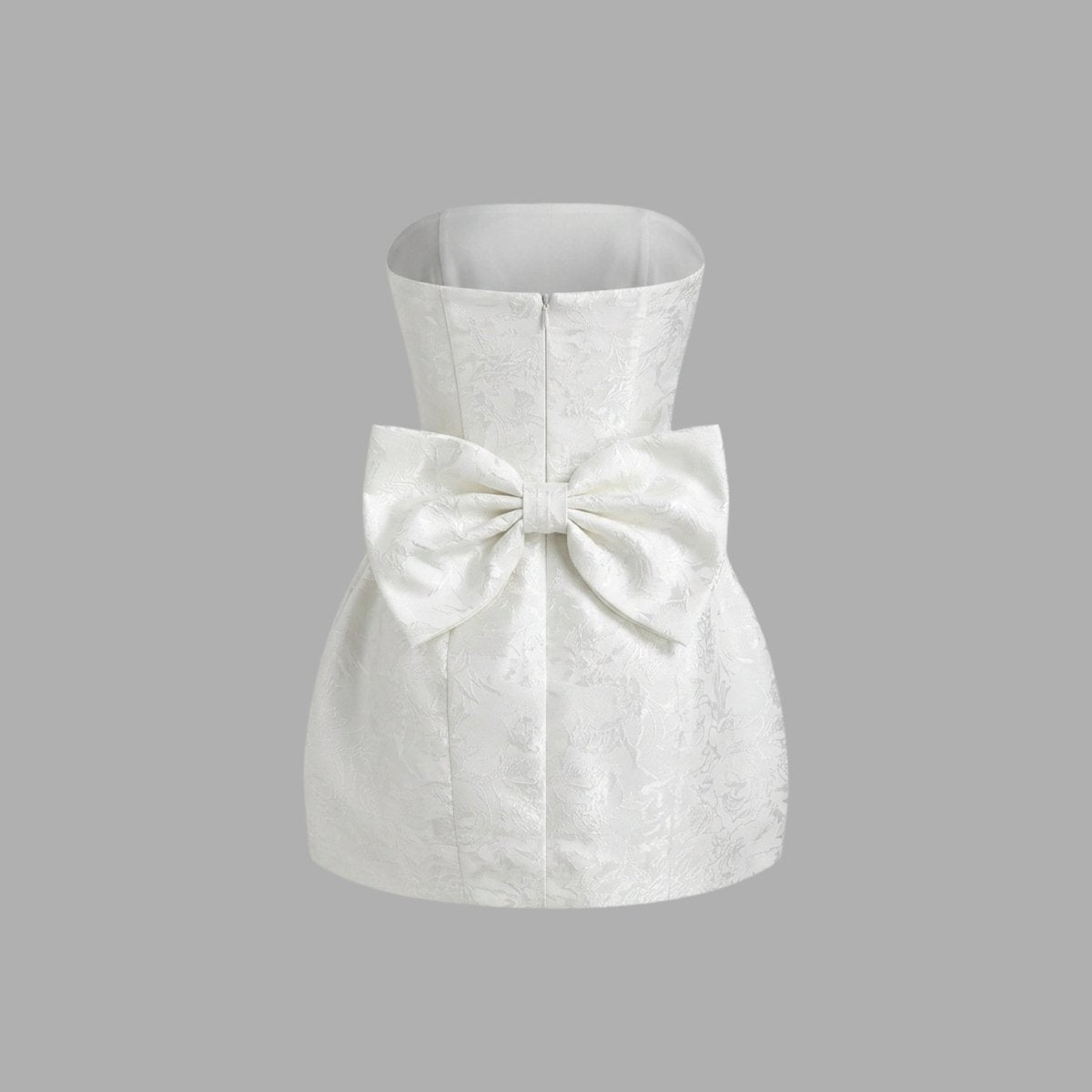 Ghost mannequin back view of white strapless mini dress showing large attached back bow and straight neckline