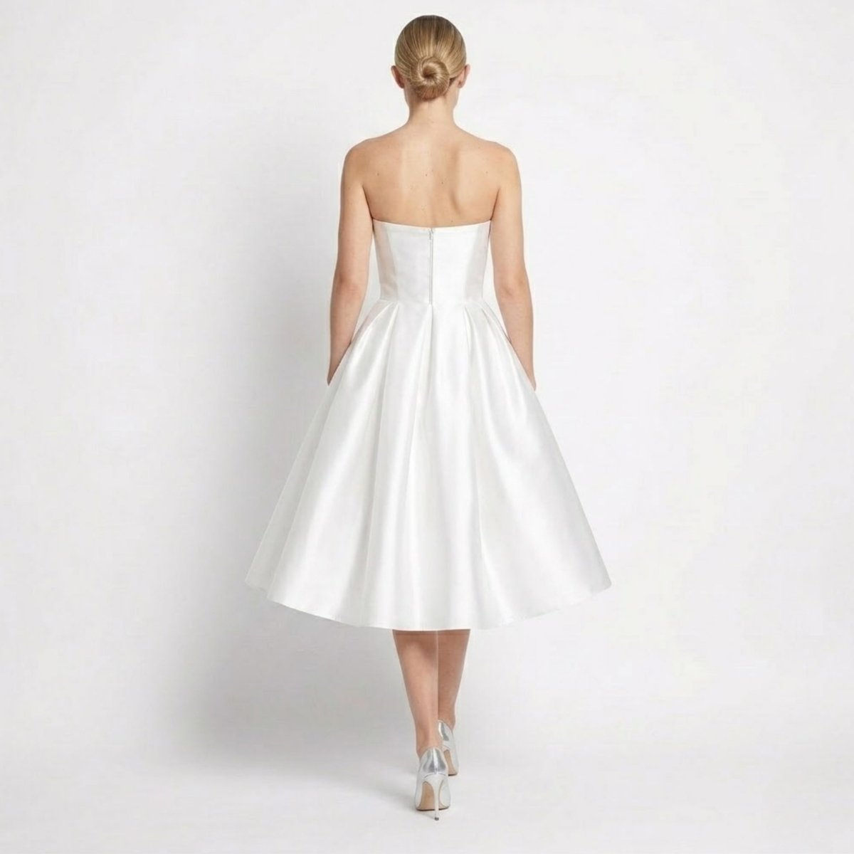 Back view of white strapless midi dress showing invisible zipper and pleated skirt details.