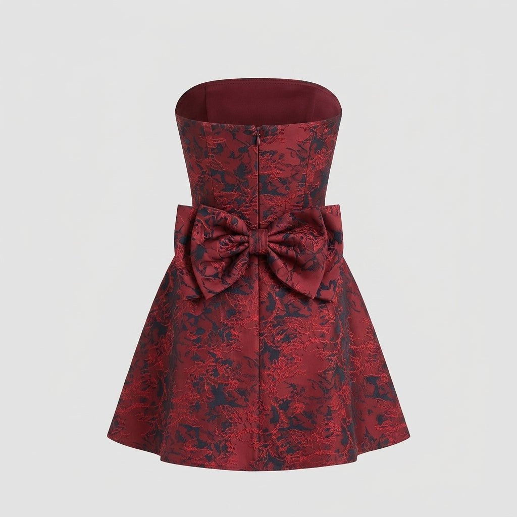 Back view of the red floral jacquard strapless mini dress on a ghost mannequin detailing the large attached bow and zipper.