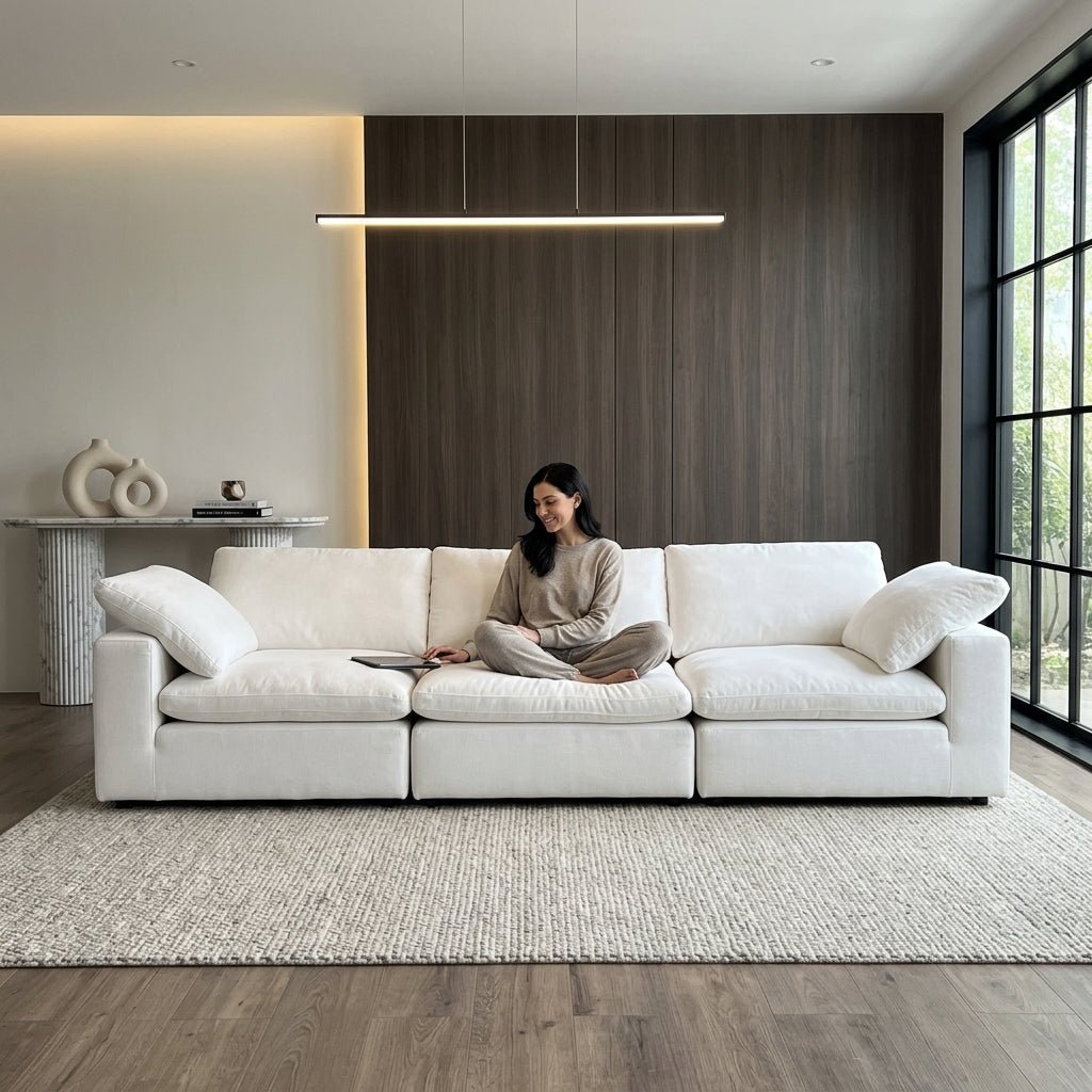 Woman comfortably relaxing with a tablet on the deep-seated Kouvr white modular lounge sofa.