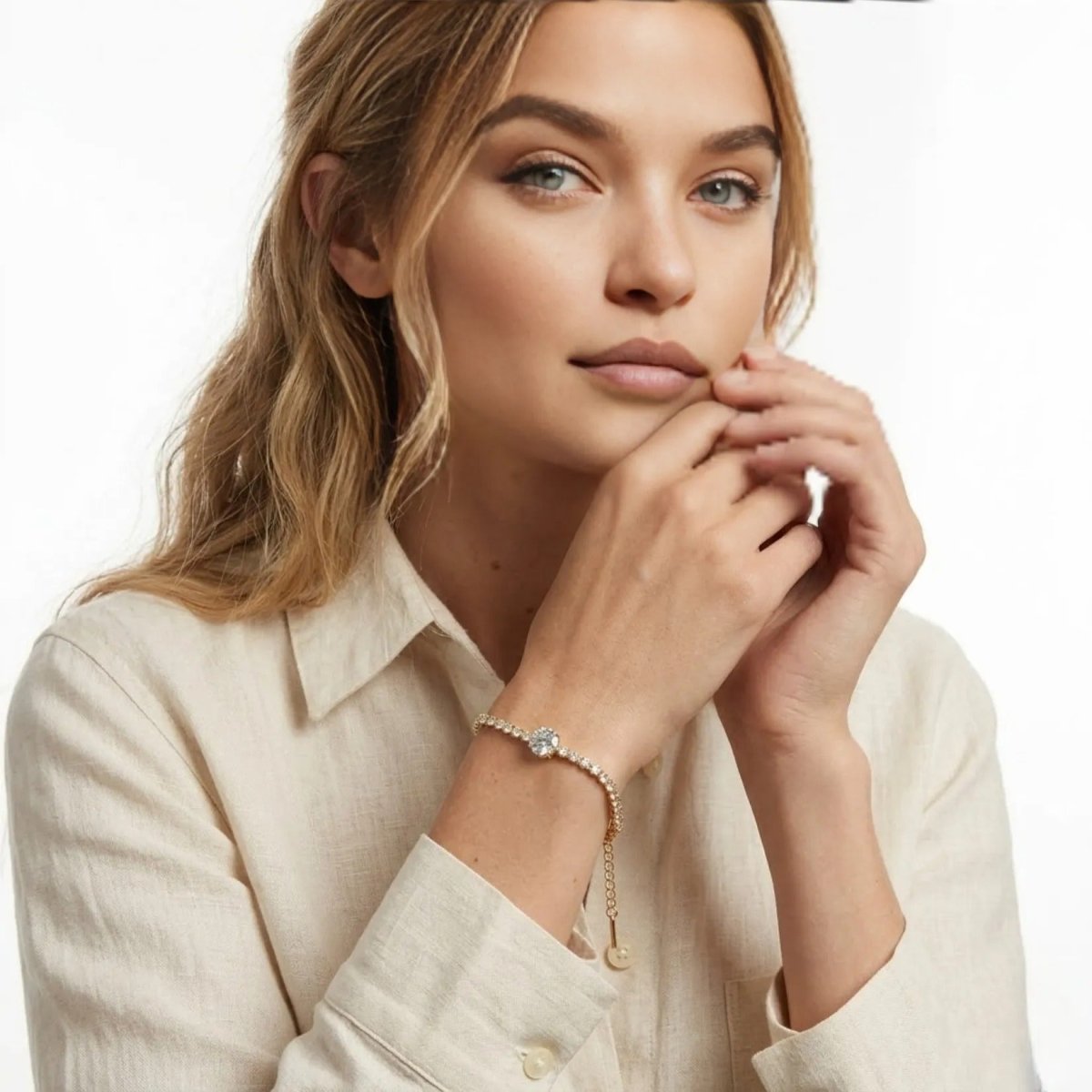 Model with blonde hair wearing a cream shirt and the Kouvr Thaliragold crystal tennis bracelet on her wrist.