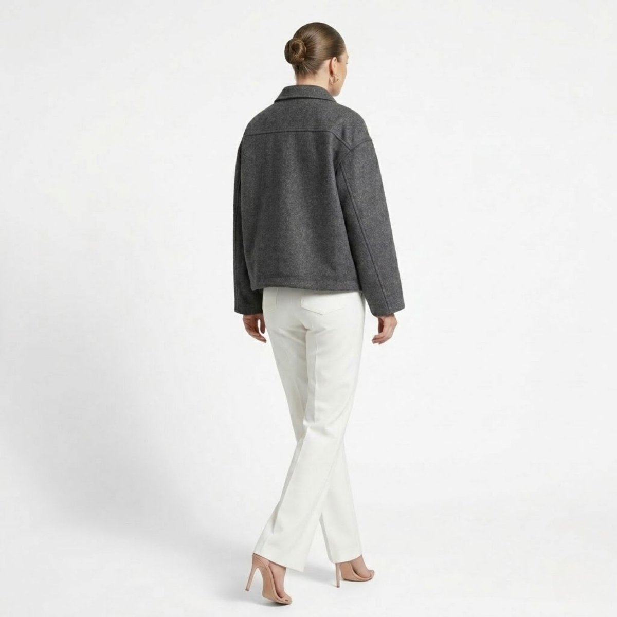 Back view of female model wearing a grey relaxed fit wool collared jacket with dropped shoulders.