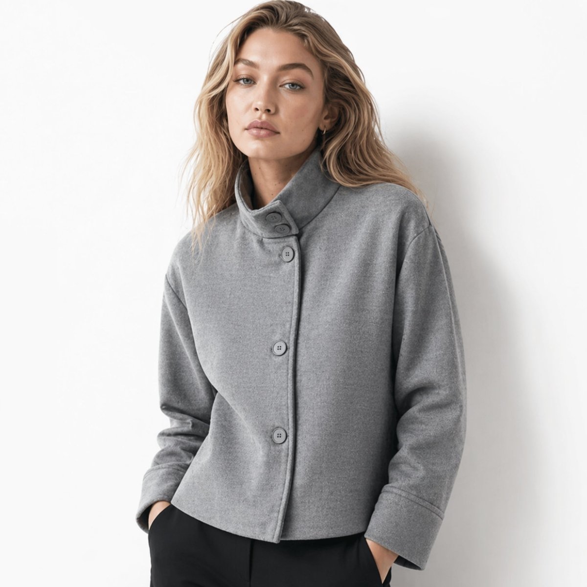 Woman wearing a grey cropped wool blend funnel neck jacket with black trousers, front view, by Kouvr.