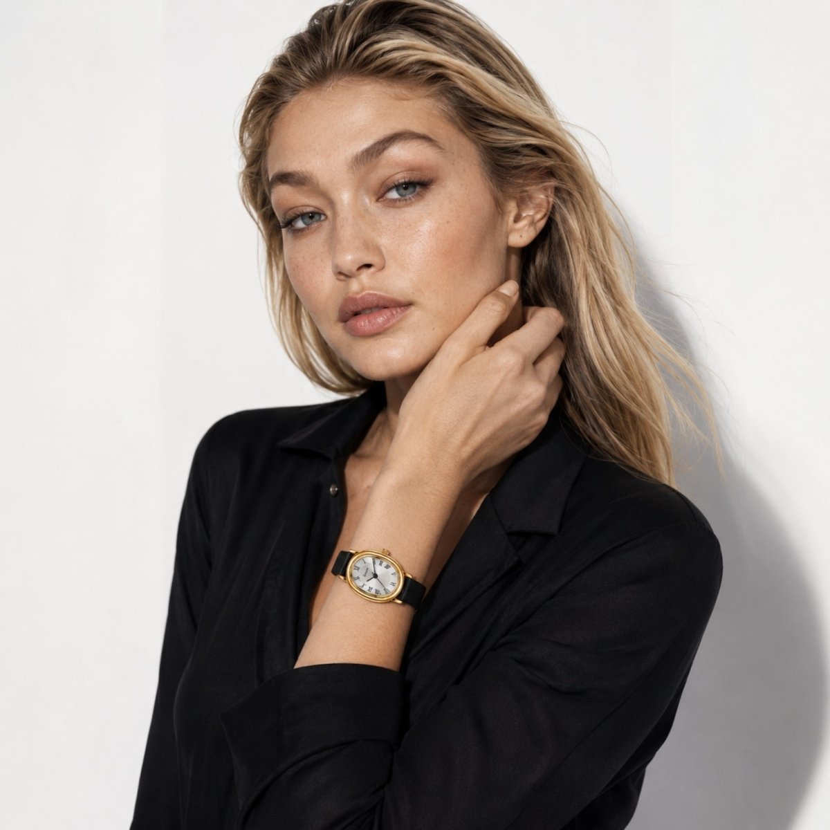 Fashion model wearing Kouvr elegant small face gold watch with black leather band paired with a black silk blouse
