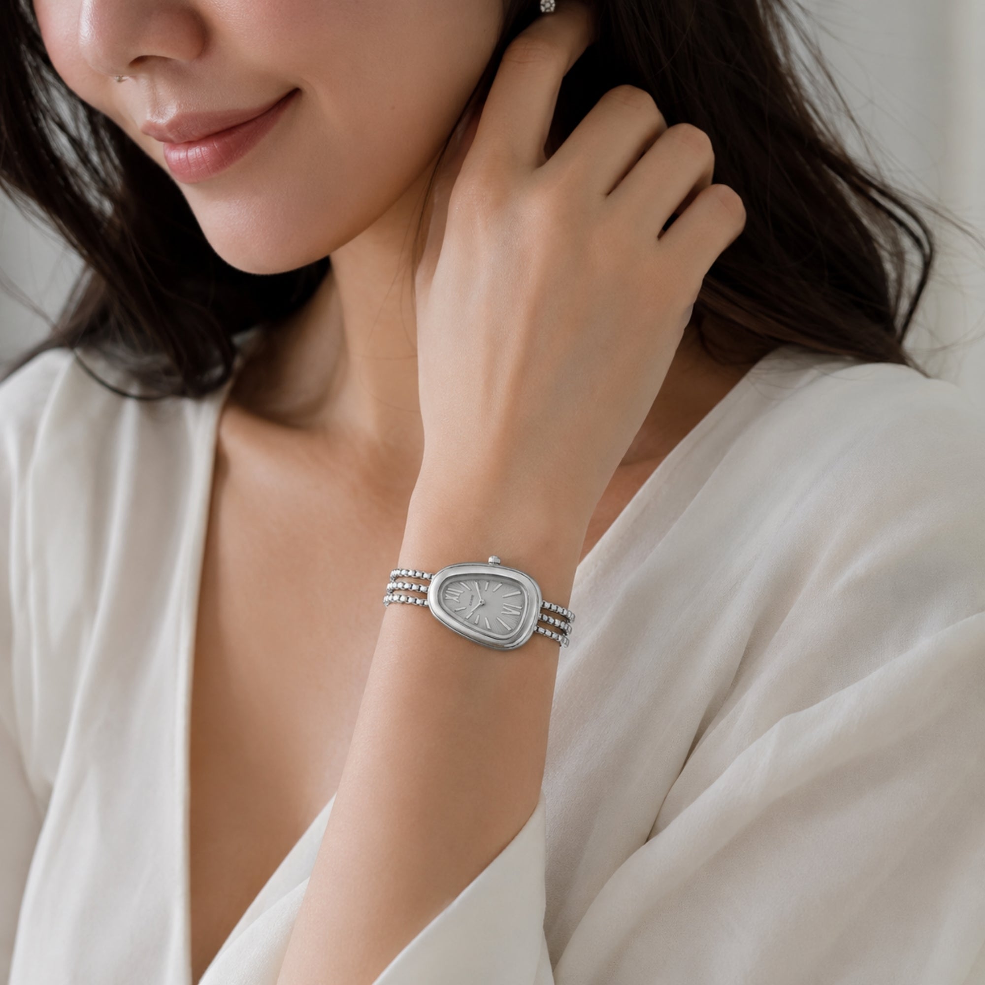 Elegant lifestyle shot of a woman wearing the Kouvr silver teardrop dial watch on her wrist, demonstrating versatile everyday luxury.